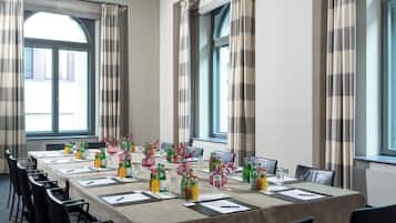 Un salón de conferencias con una larga mesa, sillas y un ventanal con cortinas.