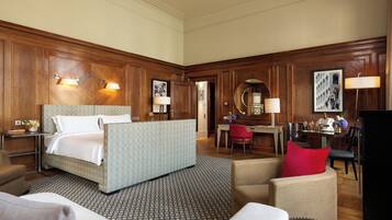 A hotel room with a bed, a desk, a chair, and a dining area.