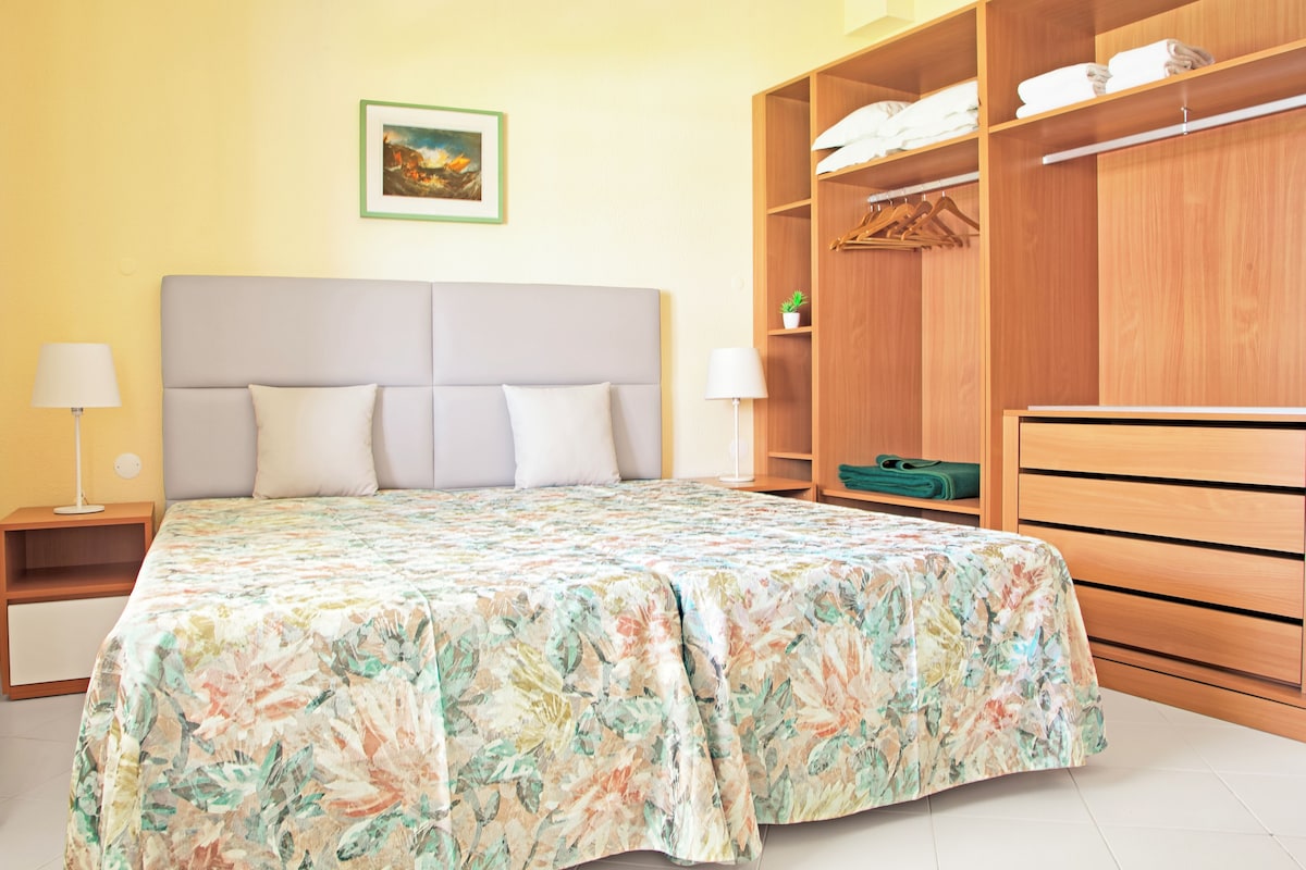 Una camera da letto con un letto, un comodino, un armadio e un quadro appeso al muro.