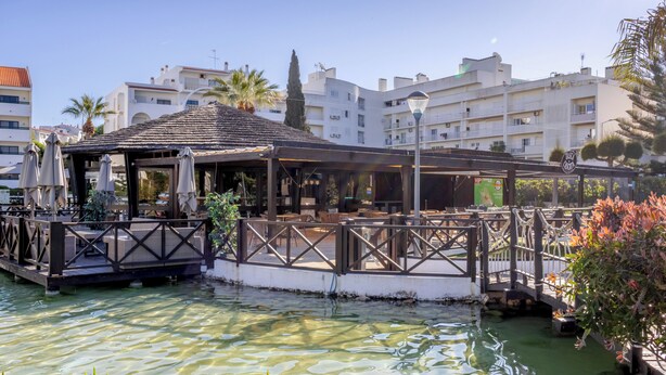 Restaurante à beira-mar com área externa, um deque de madeira e vista para a água.