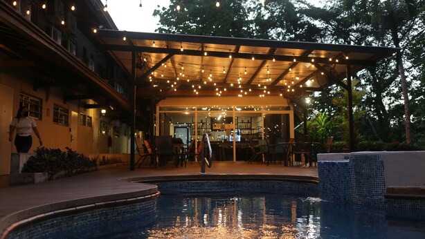 A pool area with a covered patio, outdoor seating, and a bar area.