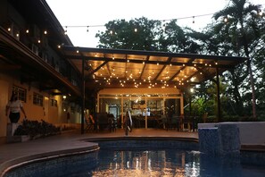 A pool area with a covered patio, outdoor seating, and a bar area. - Albrook Inn (Panama City)