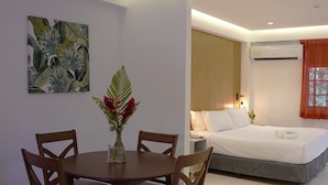 A modern hotel room with a dining area, a bed, and a large window.