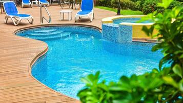 Alberca al aire libre, sombrillas en la alberca y camastros