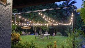 An outdoor patio with string lights, a table, chairs, and a small umbrella.