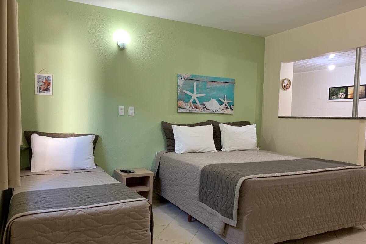 Una habitación de hotel con dos camas, una mesita de noche, un cuadro y un espejo.