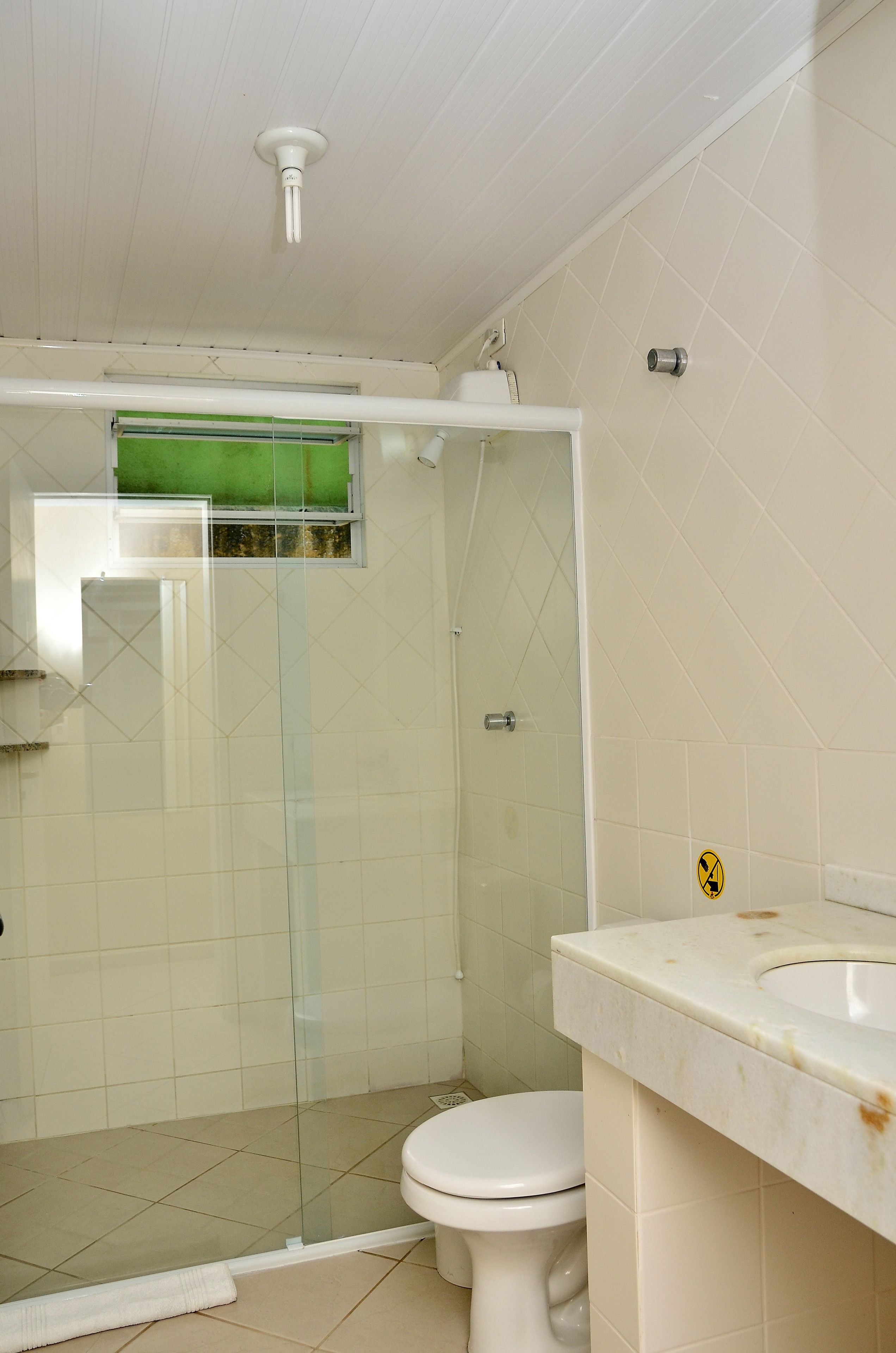 Ein Badezimmer mit Duschkabine aus Glas, Toilette und Waschbecken mit Spiegel.