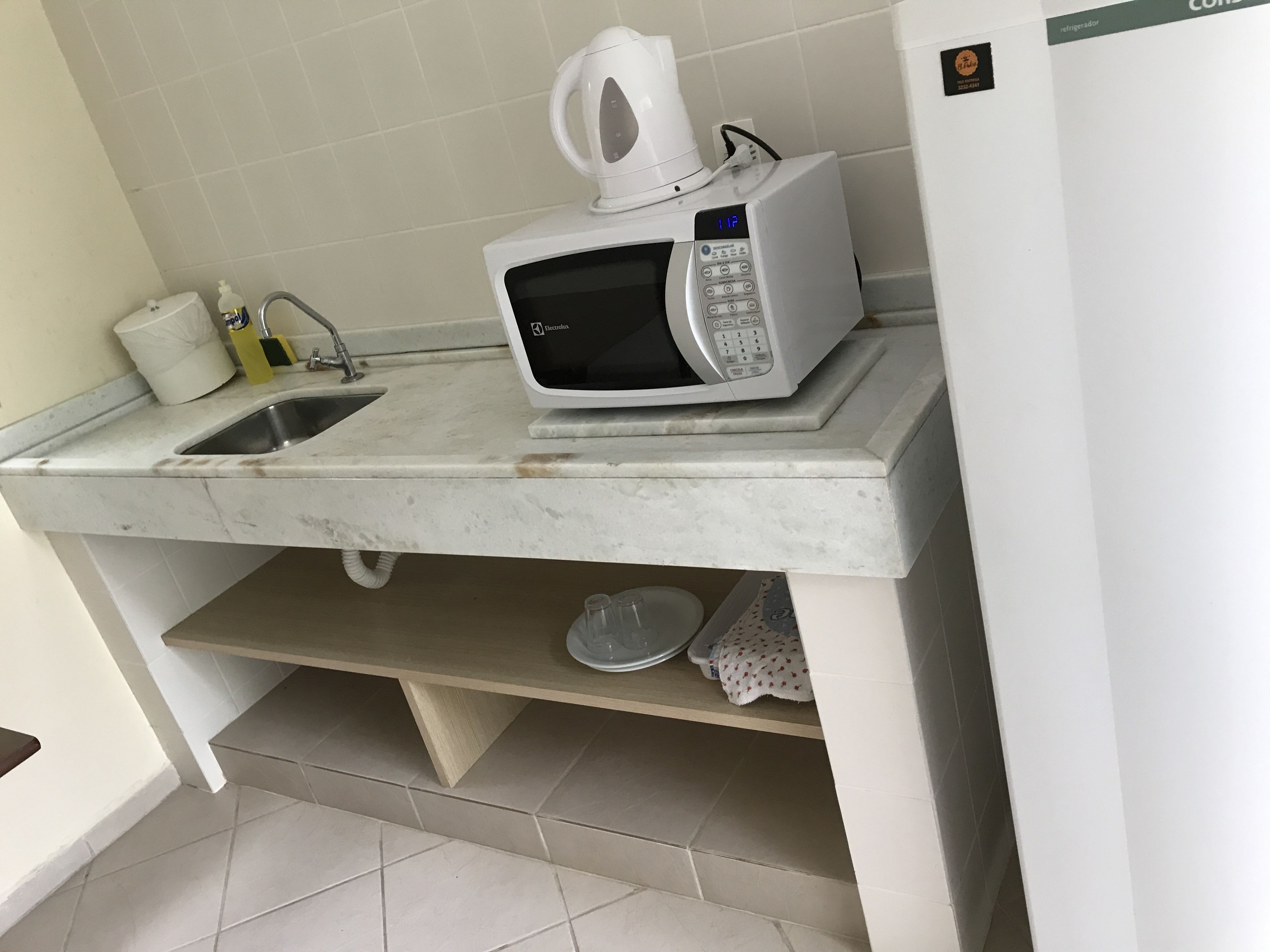 Une cuisine équipée d’un micro-ondes blanc, d’une bouilloire et d’un évier.