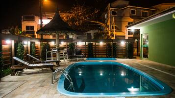 Una piscina al aire libre, sillones reclinables de piscina