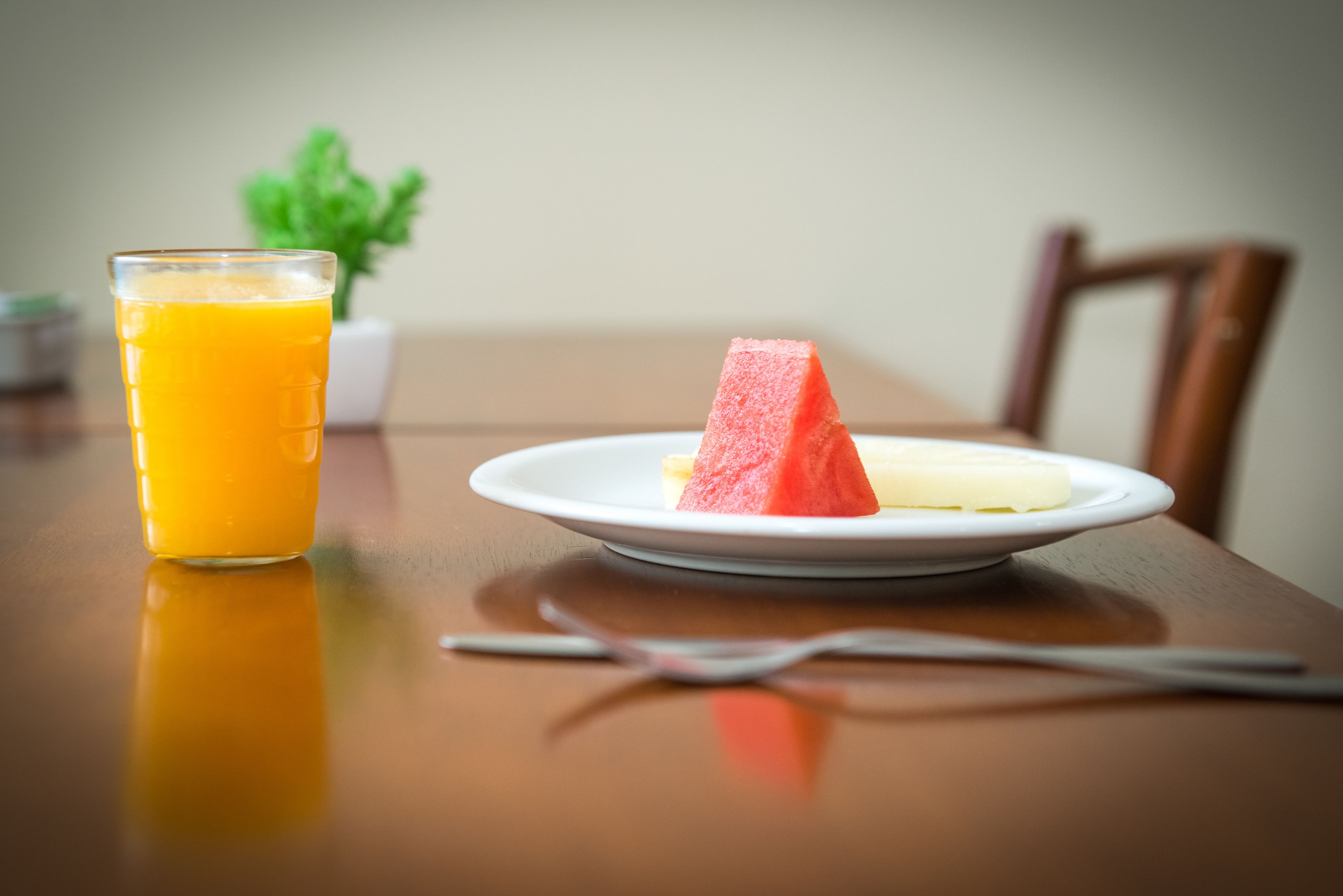 Une table à manger avec une assiette de nourriture, un verre de jus d’orange et une fourchette.