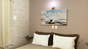 A bedroom with a bed, a nightstand, a painting of a sailboat, and a light fixture. - Pousada Mar do Leste (Florianópolis)