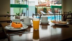 A breakfast table with a glass of orange juice, a slice of toast, and a dessert on a plate. - Pousada Mar do Leste (Florianópolis)