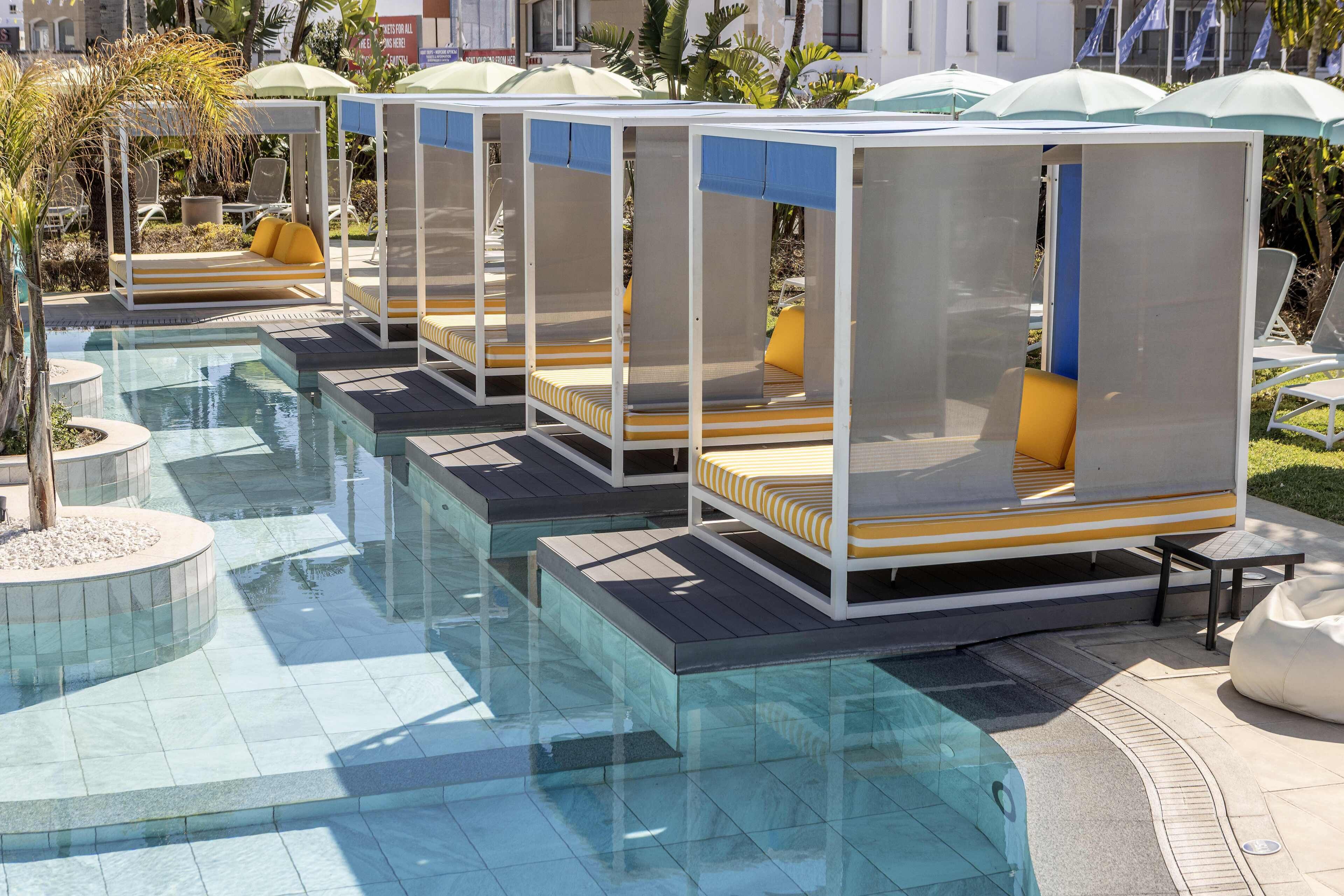 Un espace piscine avec des chaises longues et des parasols.