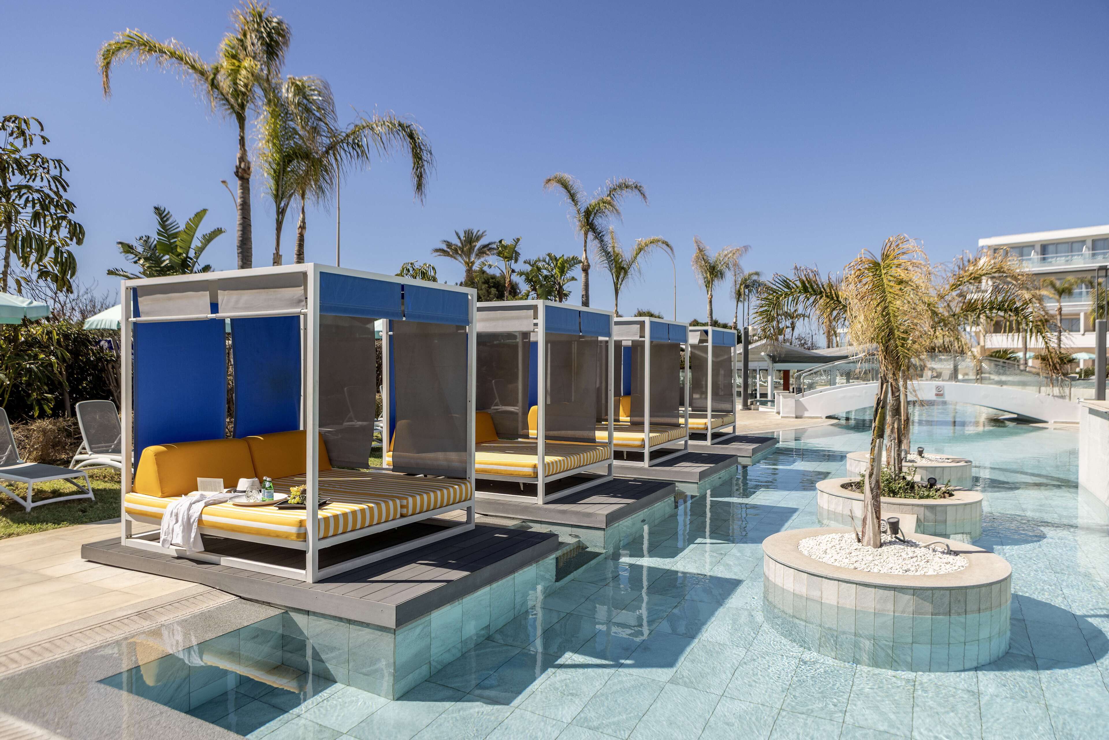 A poolside area with sun loungers and a palm tree.