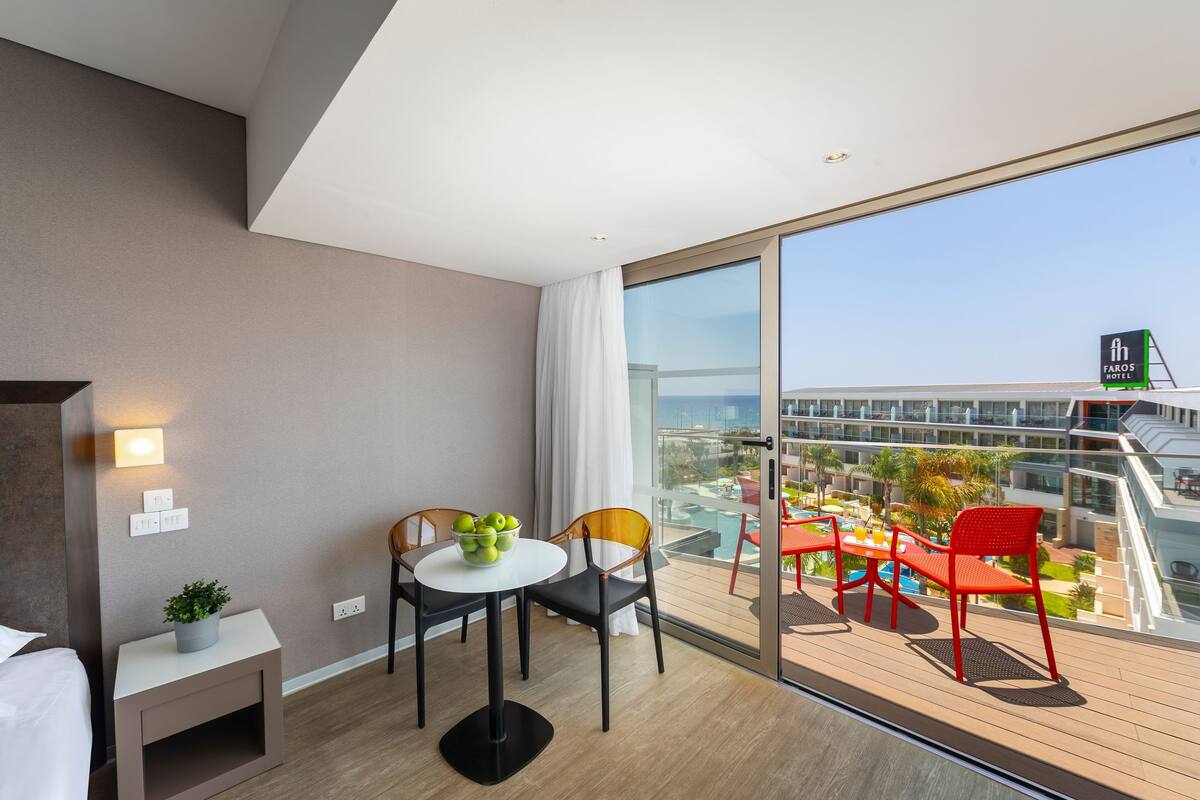 Una habitación de hotel moderna con balcón, zona de comedor y vistas a la ciudad.