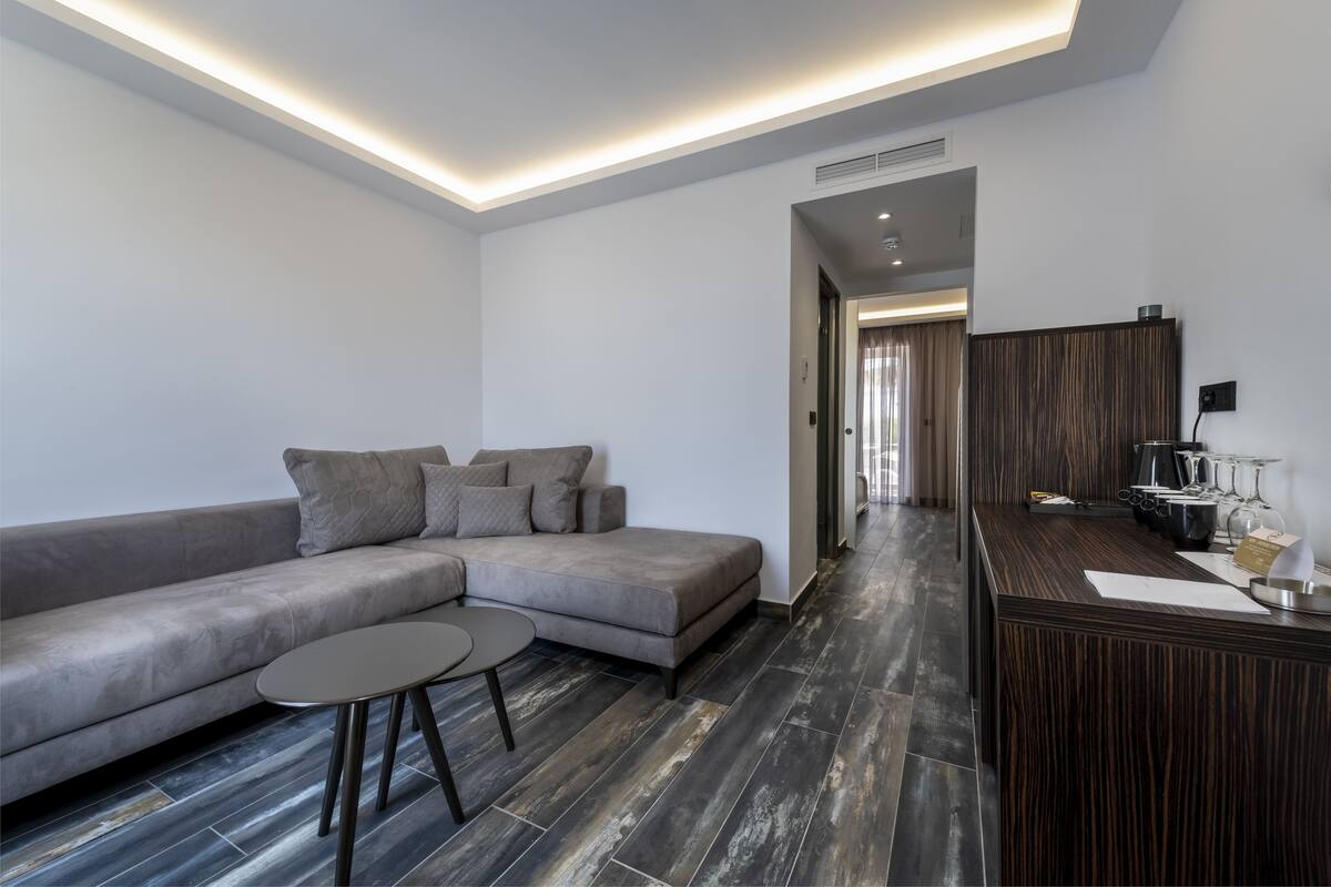 A modern living room with a grey sectional sofa, a small round table, and a dark wood accent wall.
