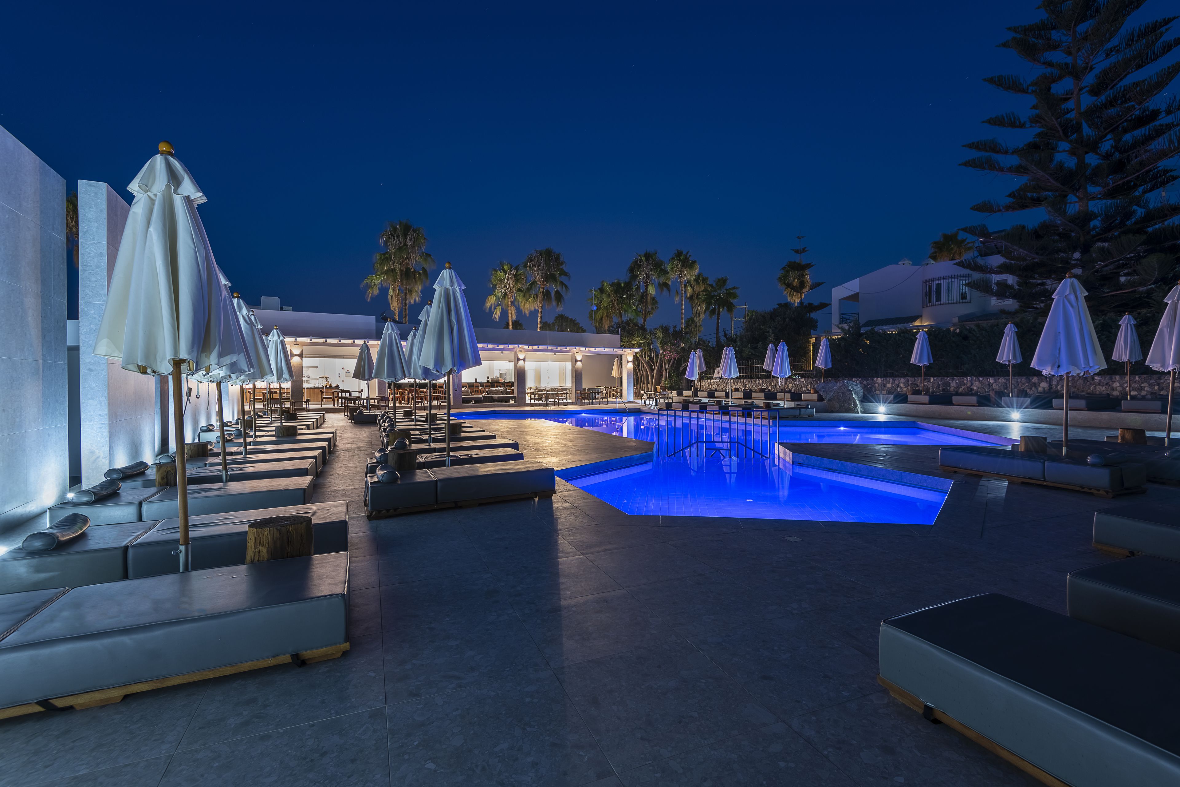 Una piscina al aire libre, sombrillas, sillones reclinables de piscina