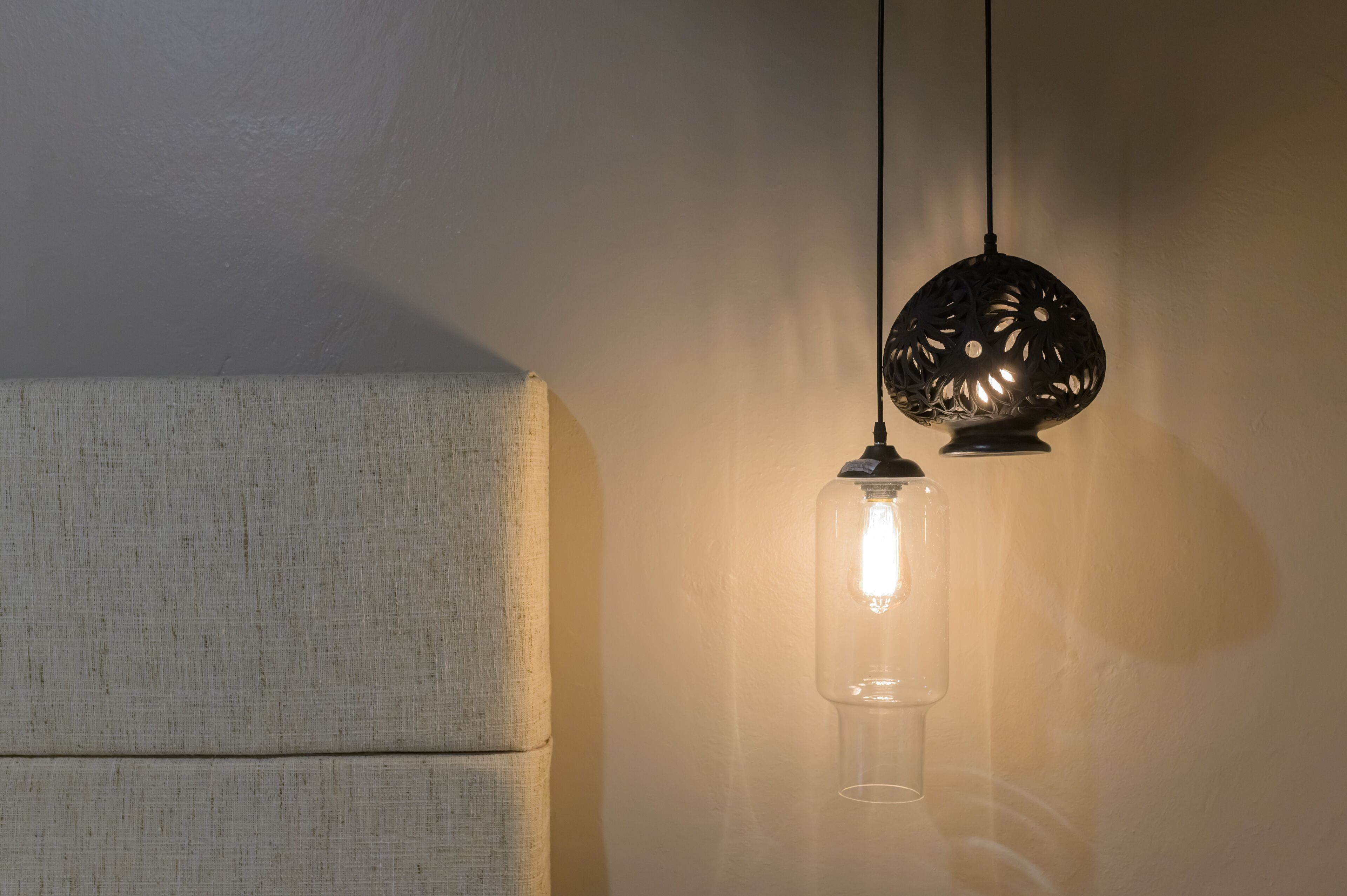 A pendant light with a clear glass enclosure and a decorative metal shade.