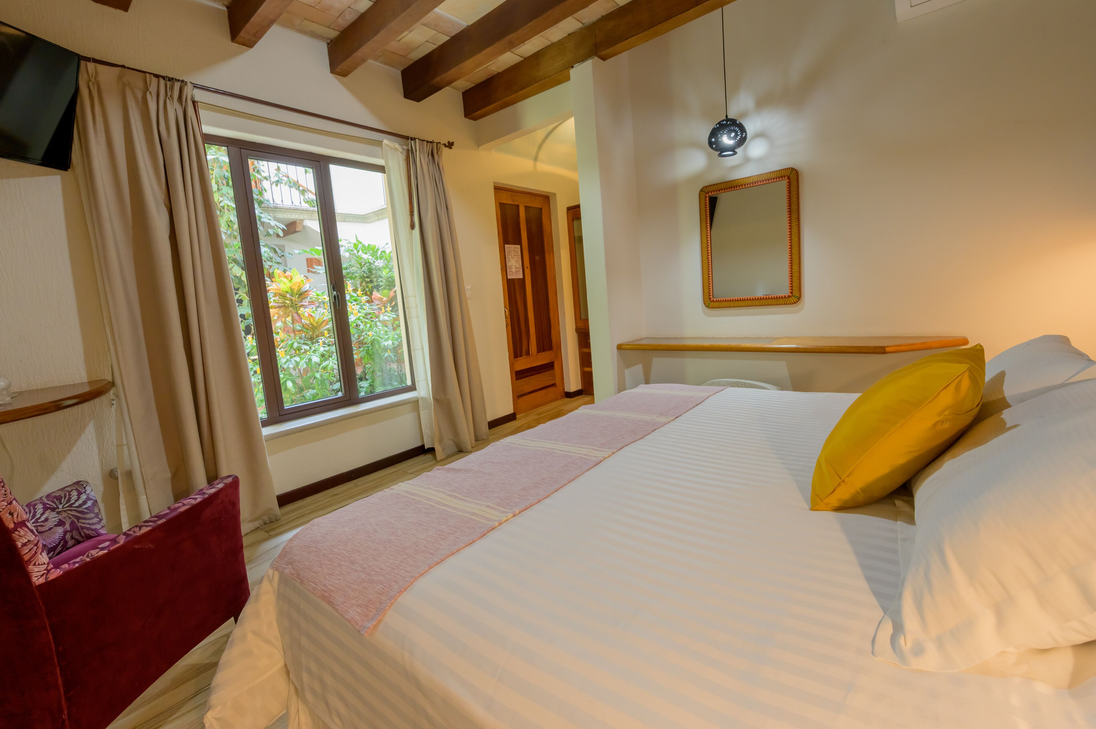 Un dormitorio con una cama grande, una mesita de noche, un espejo y una ventana con cortinas.