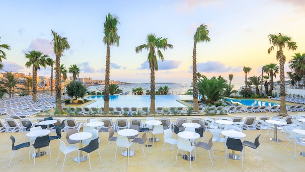 A resort with a pool, palm trees, and lounge chairs. - Salini Resort (Naxxar)