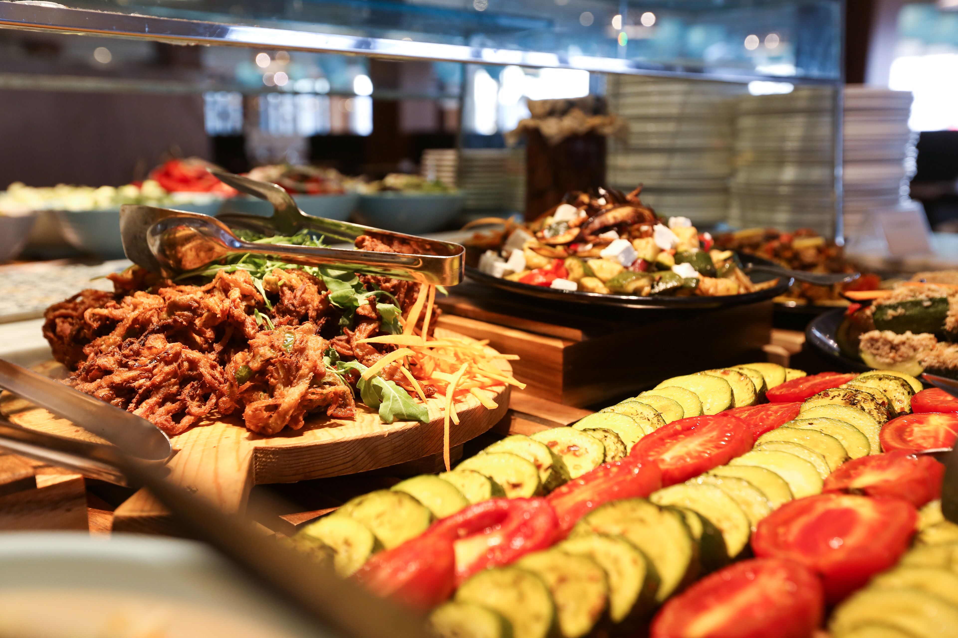 A buffet with various dishes including sliced vegetables and a meat dish.