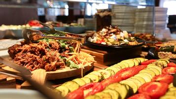 Un buffet proposant divers plats, notamment des légumes coupés en tranches et un plat de viande.