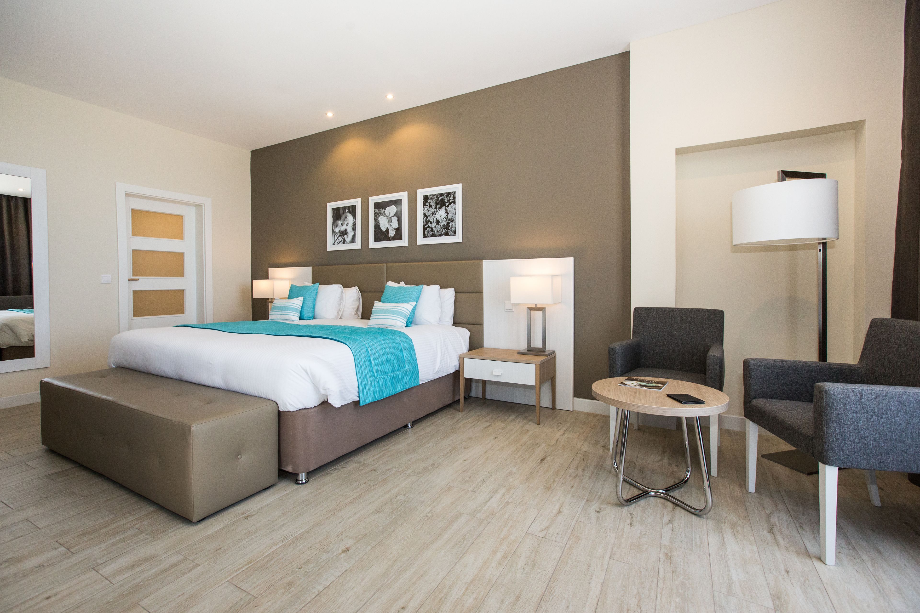 Una habitación de hotel moderna con una cama grande, mesitas de noche, un escritorio y dos sillones.