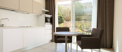A modern kitchen with white cabinets, a built-in microwave, and a round dining table with two chairs.