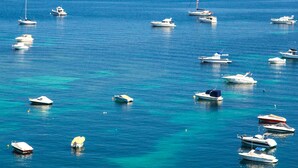A coastal area with numerous boats anchored in clear blue waters. - Salini Resort (Naxxar)