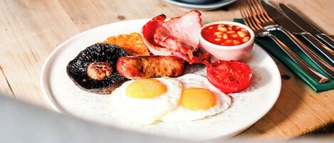 Un plato de desayuno con huevos, tocino, salchichas y frijoles.