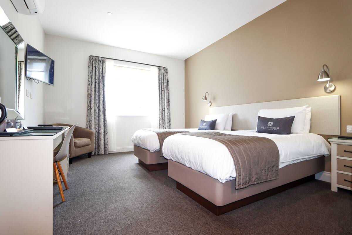 Une chambre d’hôtel avec deux lits, un bureau et une chaise.