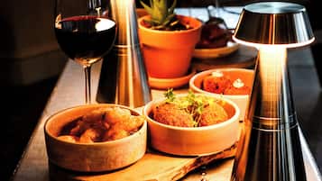 Une table garnie de différents plats, un verre de vin rouge et une lampe allumée.