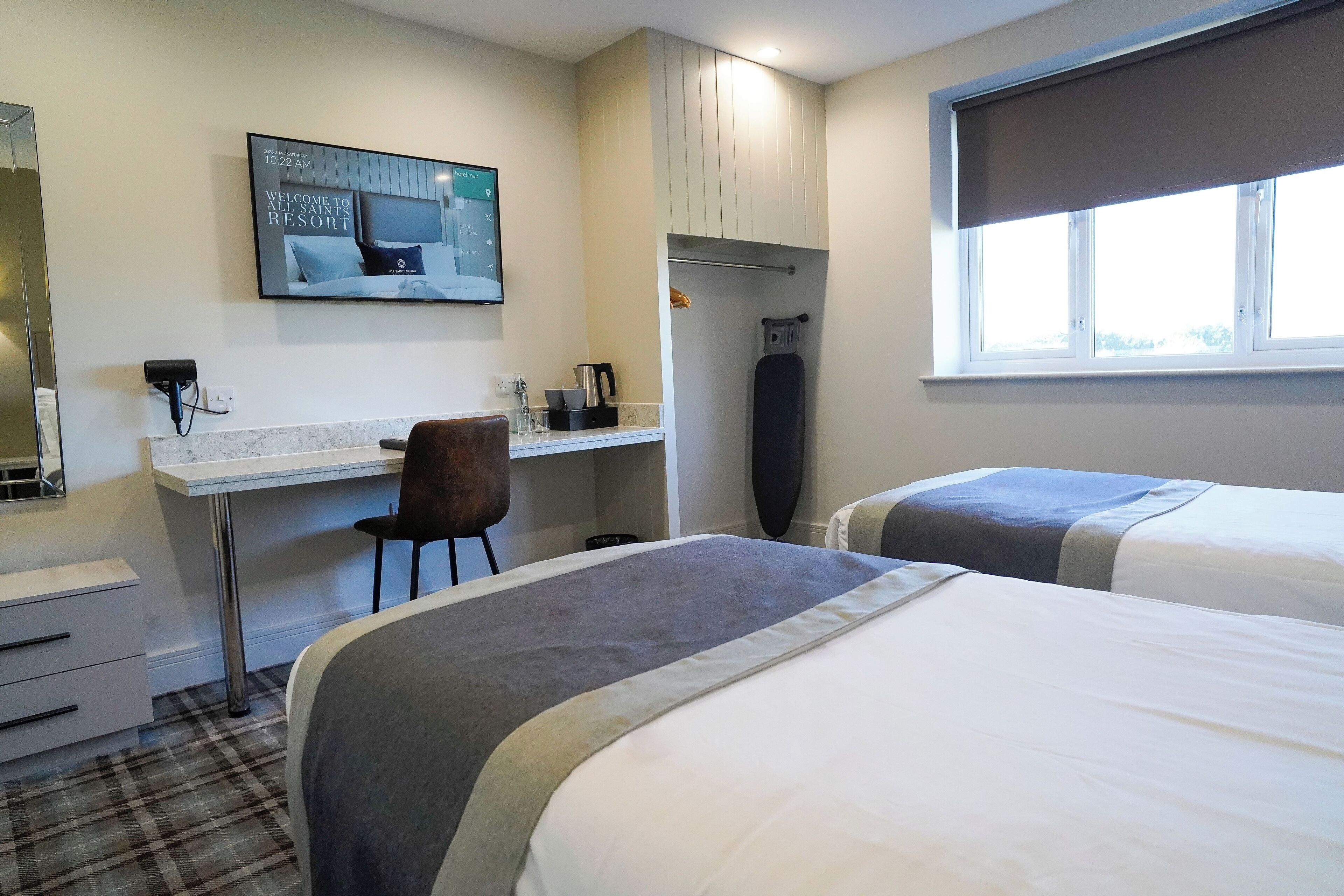 Ein Hotelzimmer mit Bett, Schreibtisch, Stuhl, Fernseher und Fenster.