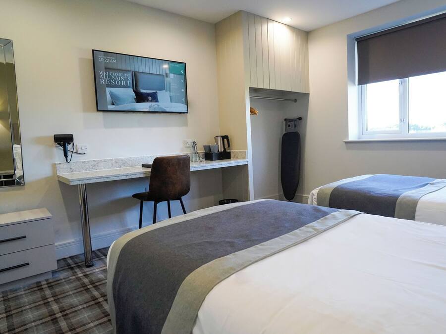 A hotel room with a bed, a desk, a chair, a TV, and a window.