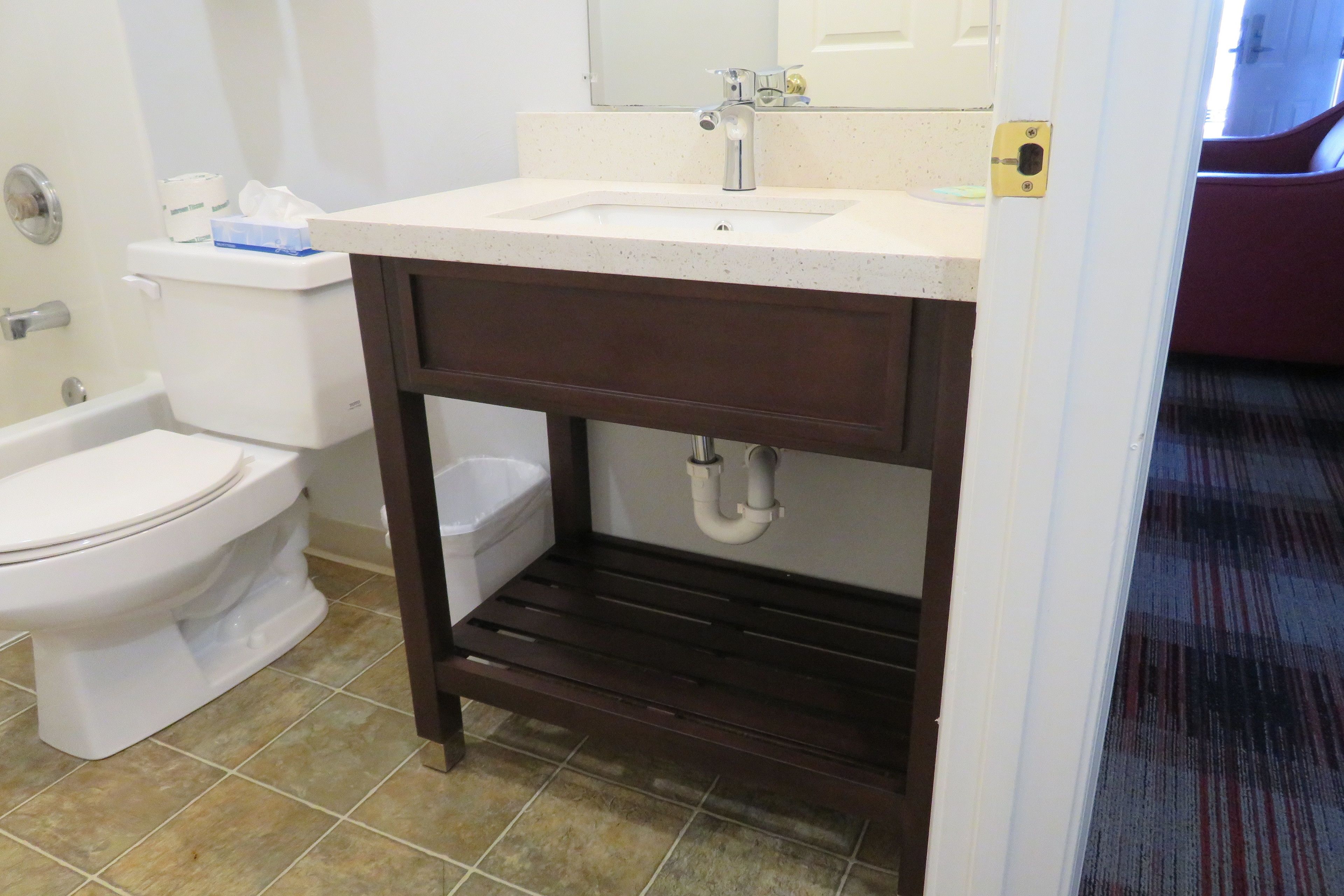 A bathroom with a white toilet, a sink with a mirror above it, and a shower area.