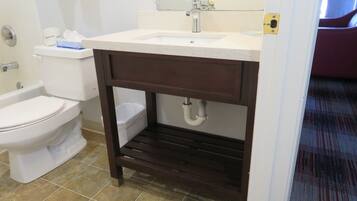 A bathroom with a white toilet, a sink with a mirror above it, and a shower area.