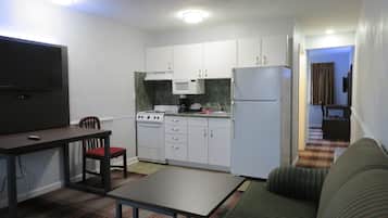 Un espacio habitable compacto con kitchenette, una mesa de comedor con sillas y un sofá.