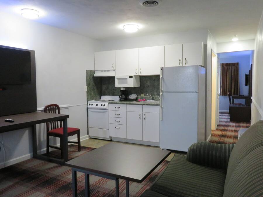 Un espacio habitable compacto con kitchenette, una mesa de comedor con sillas y un sofá.