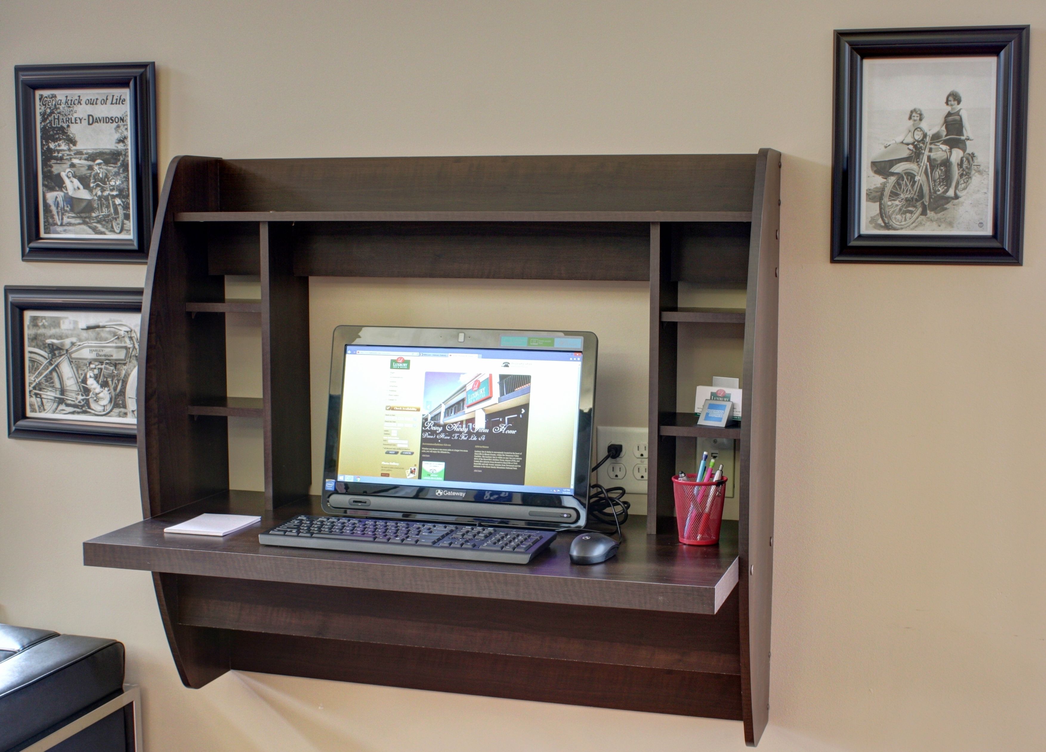A laptop on a wooden desk with a shelf above it.