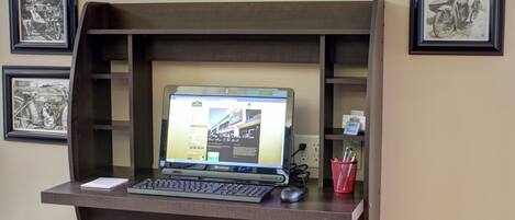 A laptop on a wooden desk with a shelf above it.