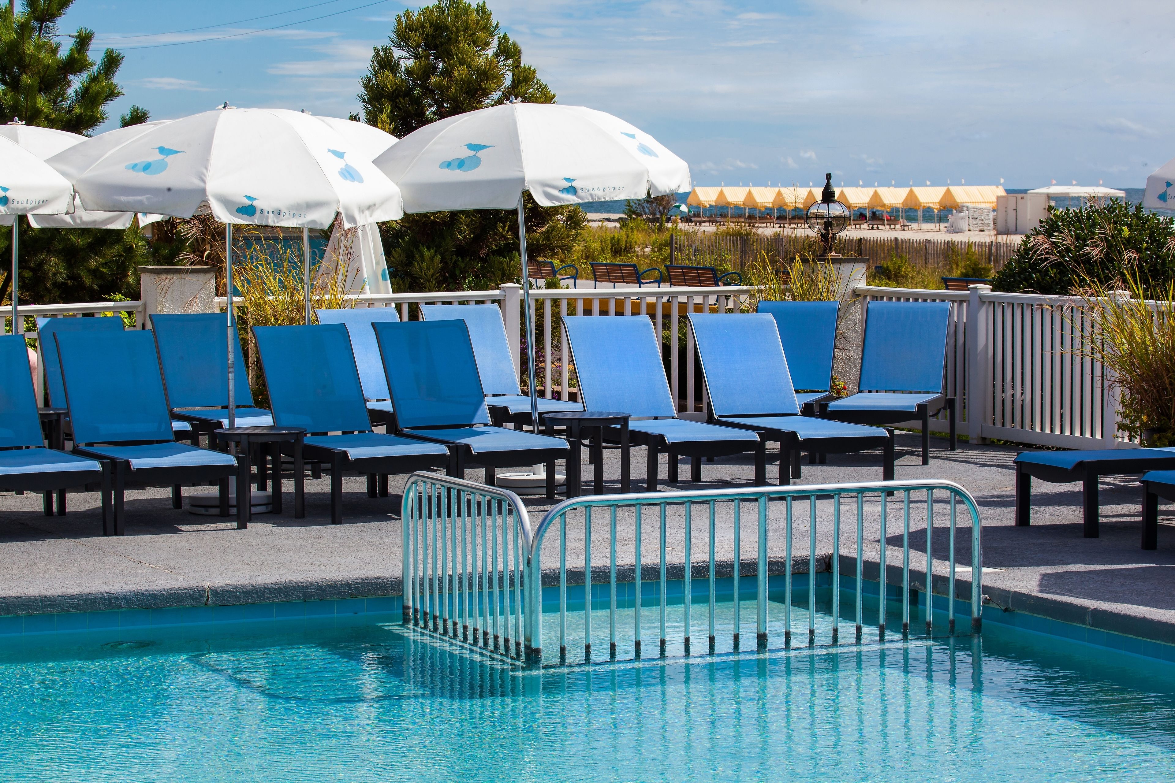 Ein Poolbereich mit blauen Liegestühlen und weißen Sonnenschirmen.