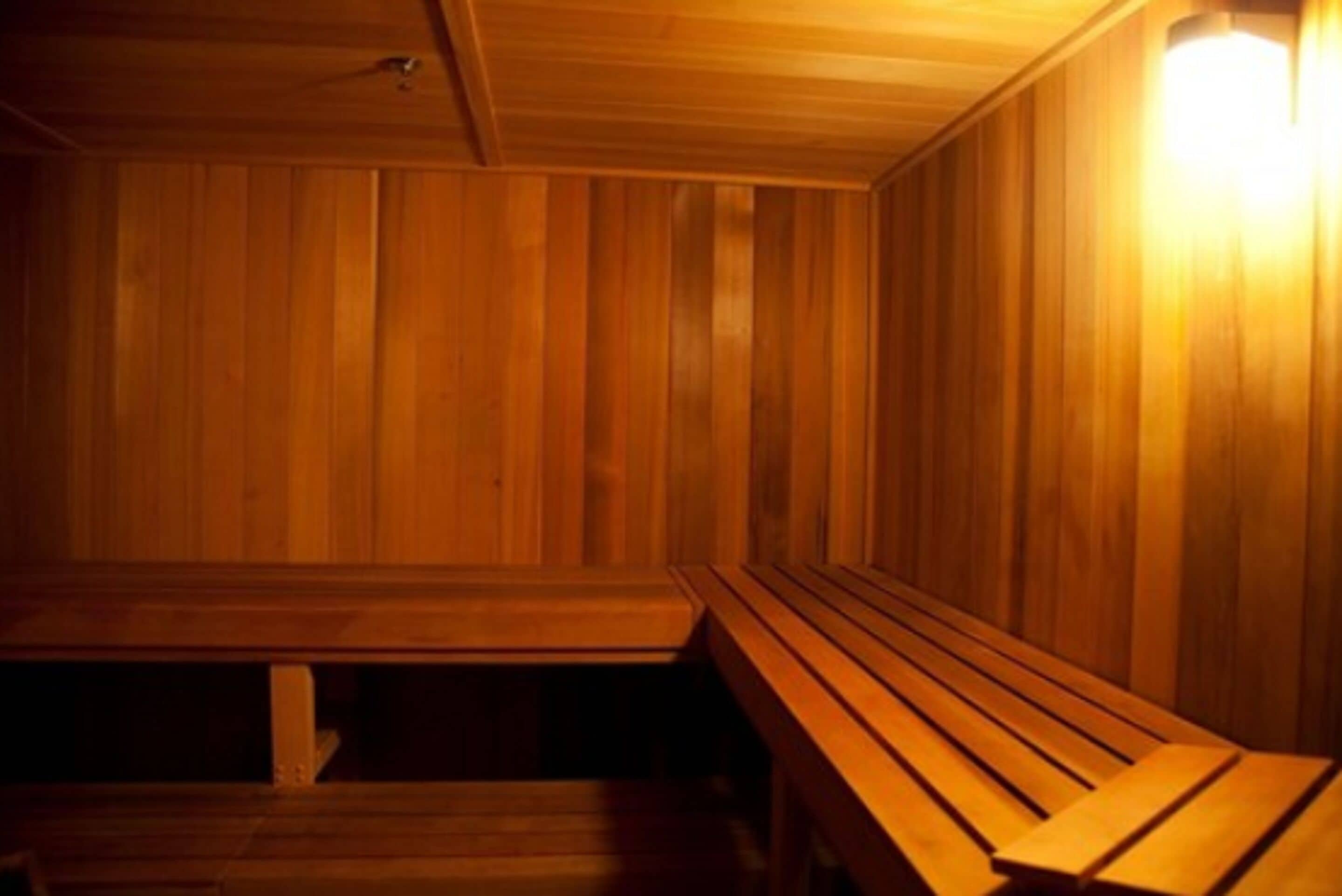 A wooden sauna with benches and a wall-mounted light.