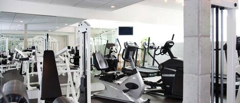 A gym with various exercise equipment, including treadmills, weight machines, and a rowing machine.