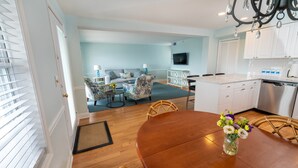 A modern kitchen with white cabinets, a stainless steel dishwasher, and a wooden dining table with chairs.