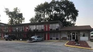 A motel with a two-story building, a parking lot, and a small front porch area. - Budget Host Village Inn (Kirksville)