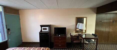 Habitación de hotel con dos camas, un escritorio con lámpara, televisión, microondas y cómoda.