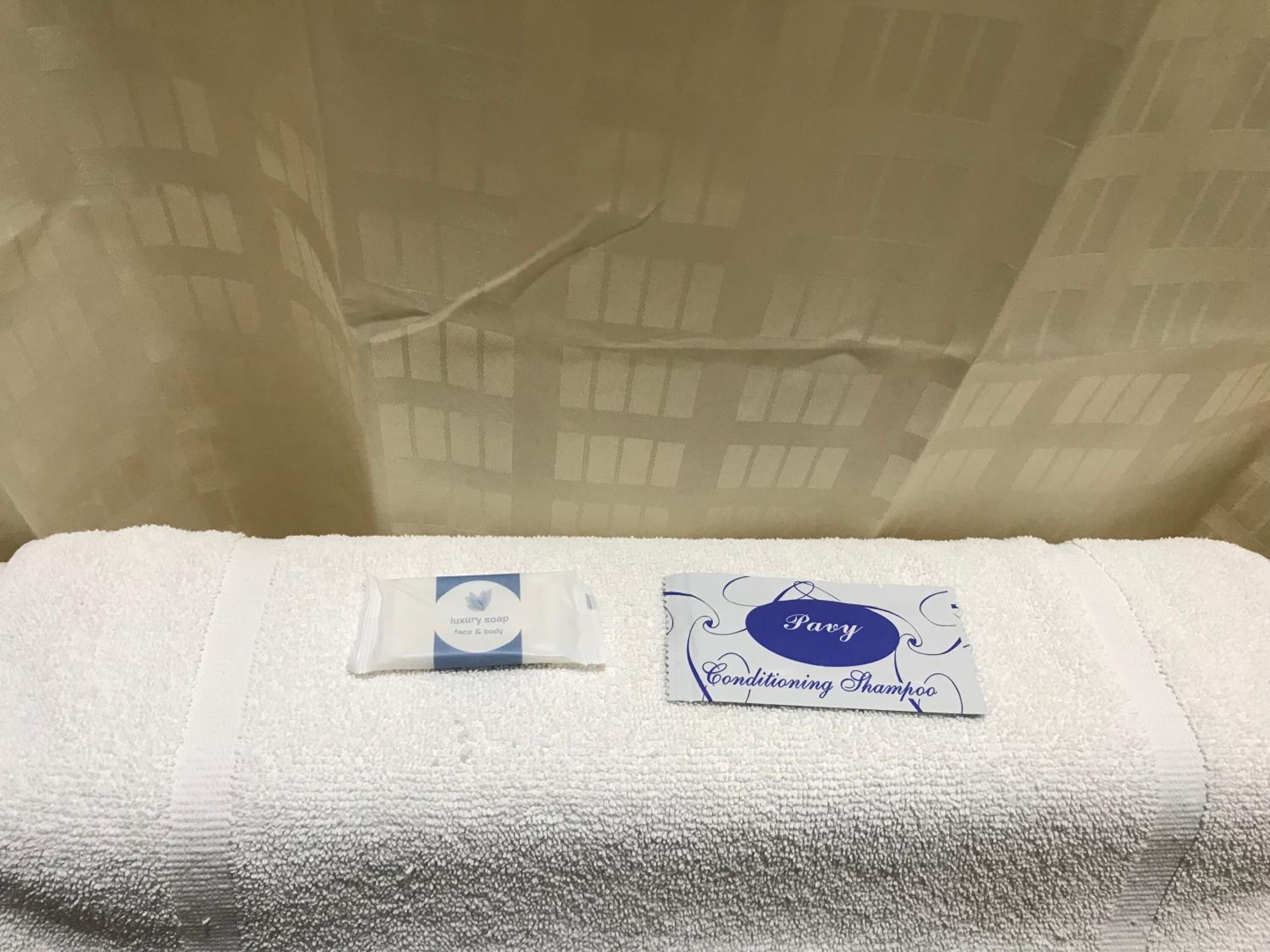 A white towel with a small white bottle and a card labeled "Pavy Conditioning Shampoo" on it.