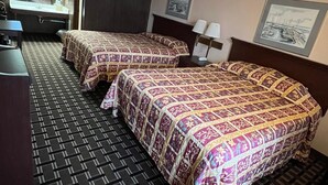 A hotel room with two beds, a desk, a chair, a sink, and a mirror. - Budget Host Village Inn (Kirksville)