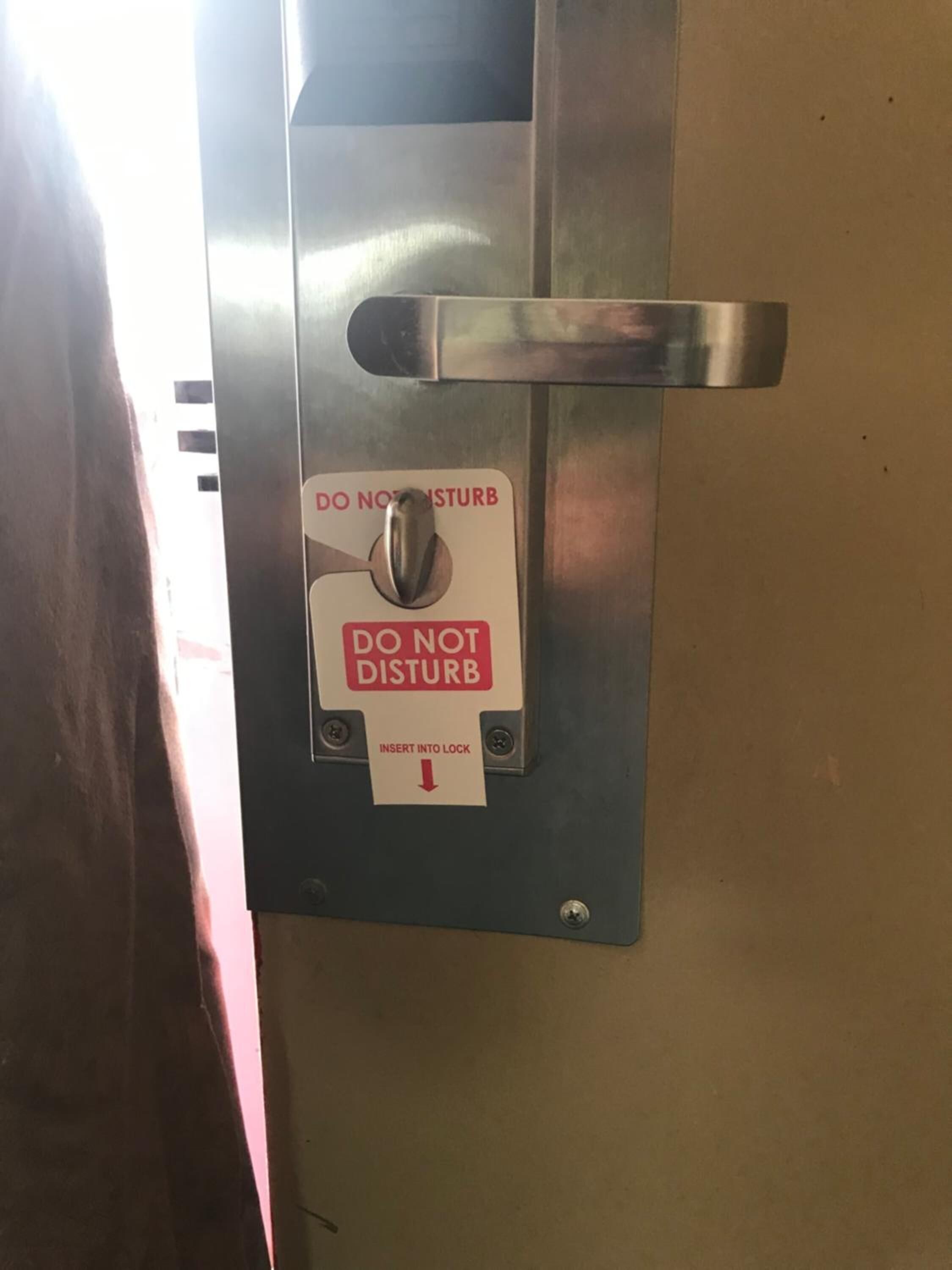 A metallic door with a 'DO NOT DISTURB' sign and a lock mechanism.