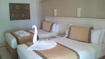 A hotel room with two beds, a decorative swan on the left bed, and a telephone on the right bed.